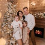 a family standing happily next to a Christmas tree