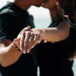 a couple kissing , holding hands and showing their rings