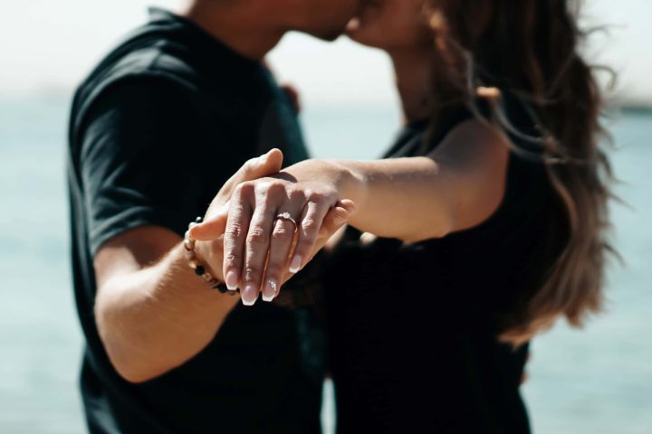 a couple kissing , holding hands and showing their rings