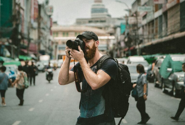 A man in the middle of street taking a photo with his camera