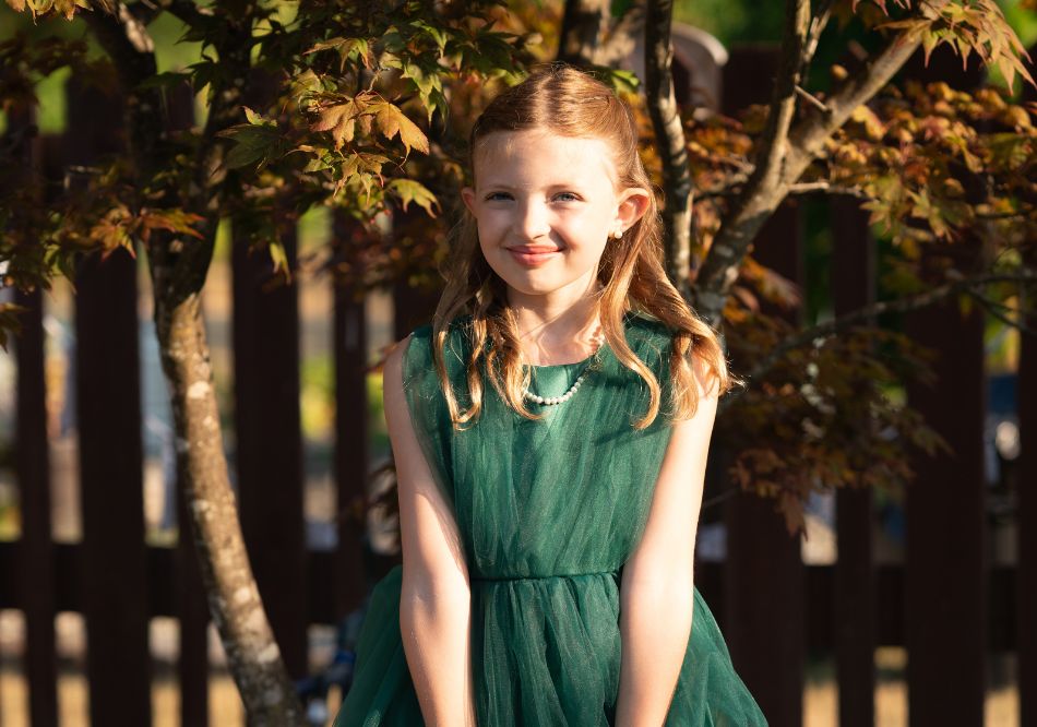 Picture of a little girl standing in front of trees