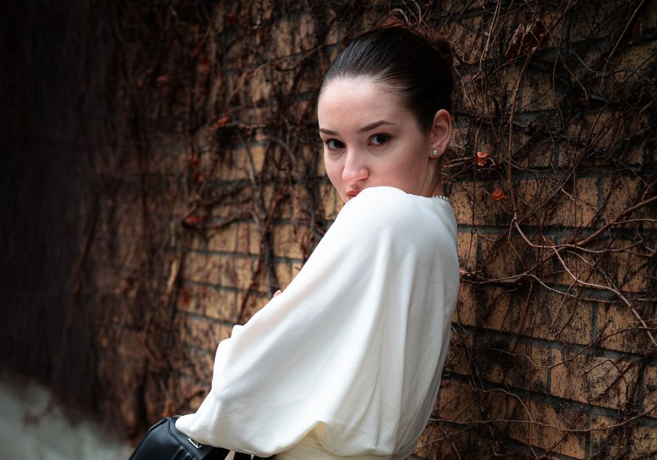 A woman posing in a photoshoot with a wall in the background