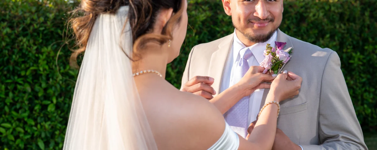 wedding photo of a couple, bride attaching a flower