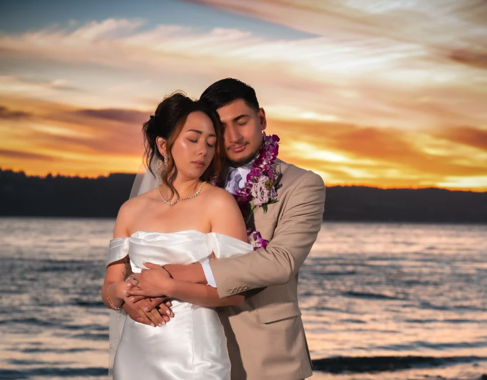 Wedding photo of a couple holding each other with a sunset backdrop