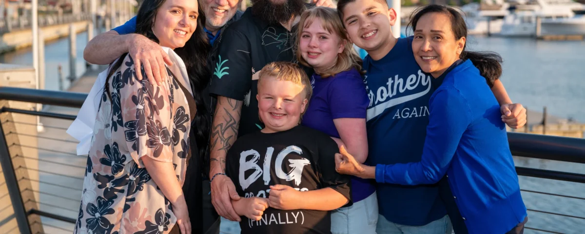 all members of a family standing and hugging each other next to the sea