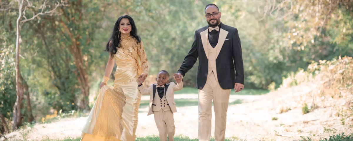 a family of three walking outside in a garden