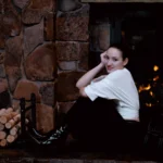 portrait of a girl sitting next to a fireplace