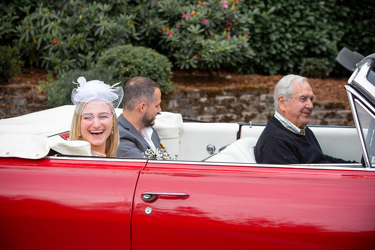 A couple in a red car on their wedding day