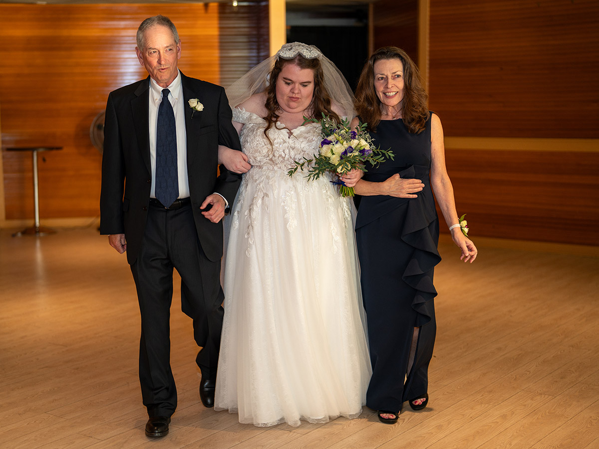 The bride is walking down the aisle with her family.