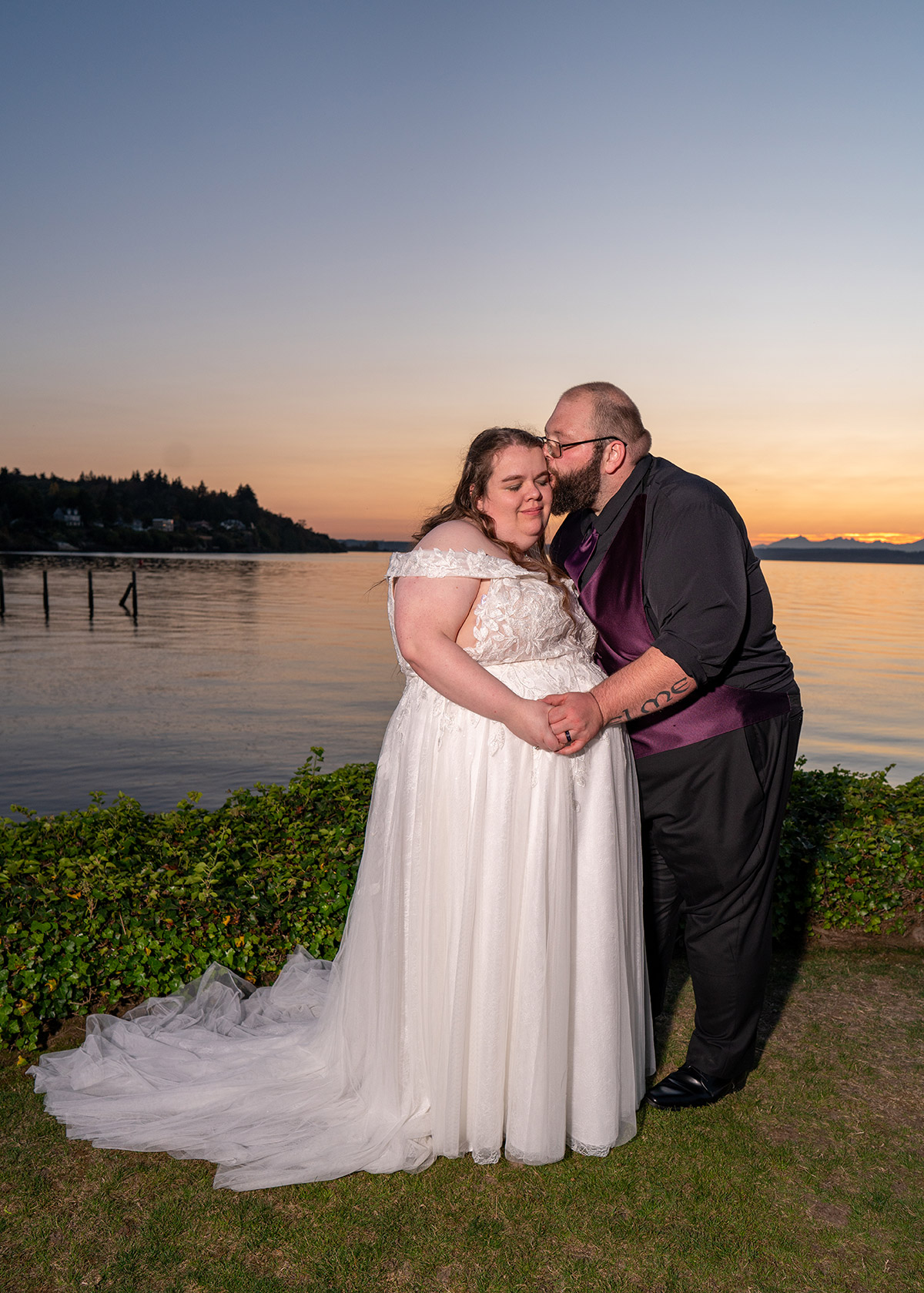 The groom is kissing the bride on the cheek.
