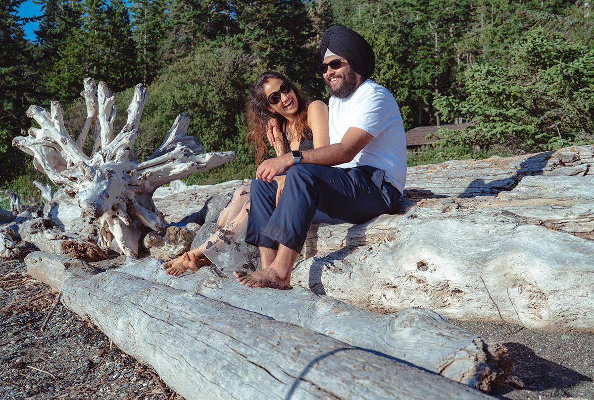 A couple sitting on logs on their engagement day