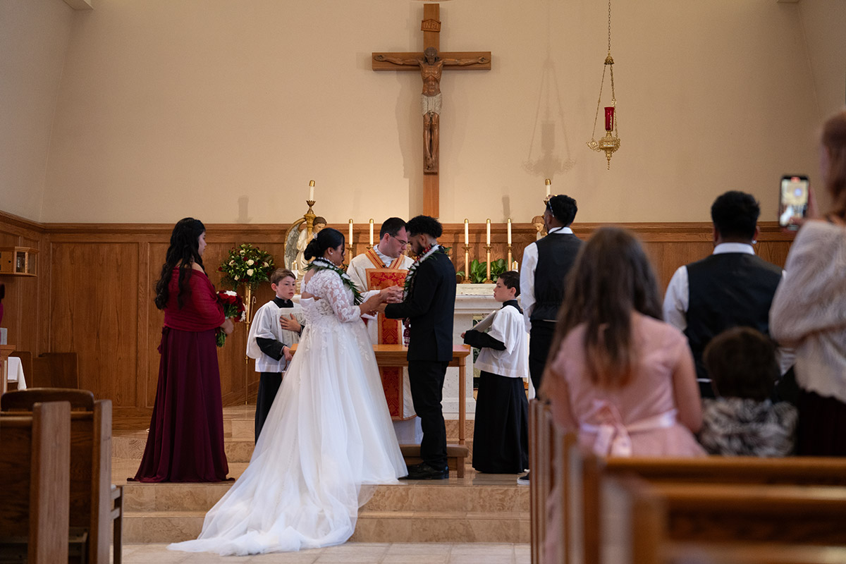 A wide photo of the bride and the groom in the church.
