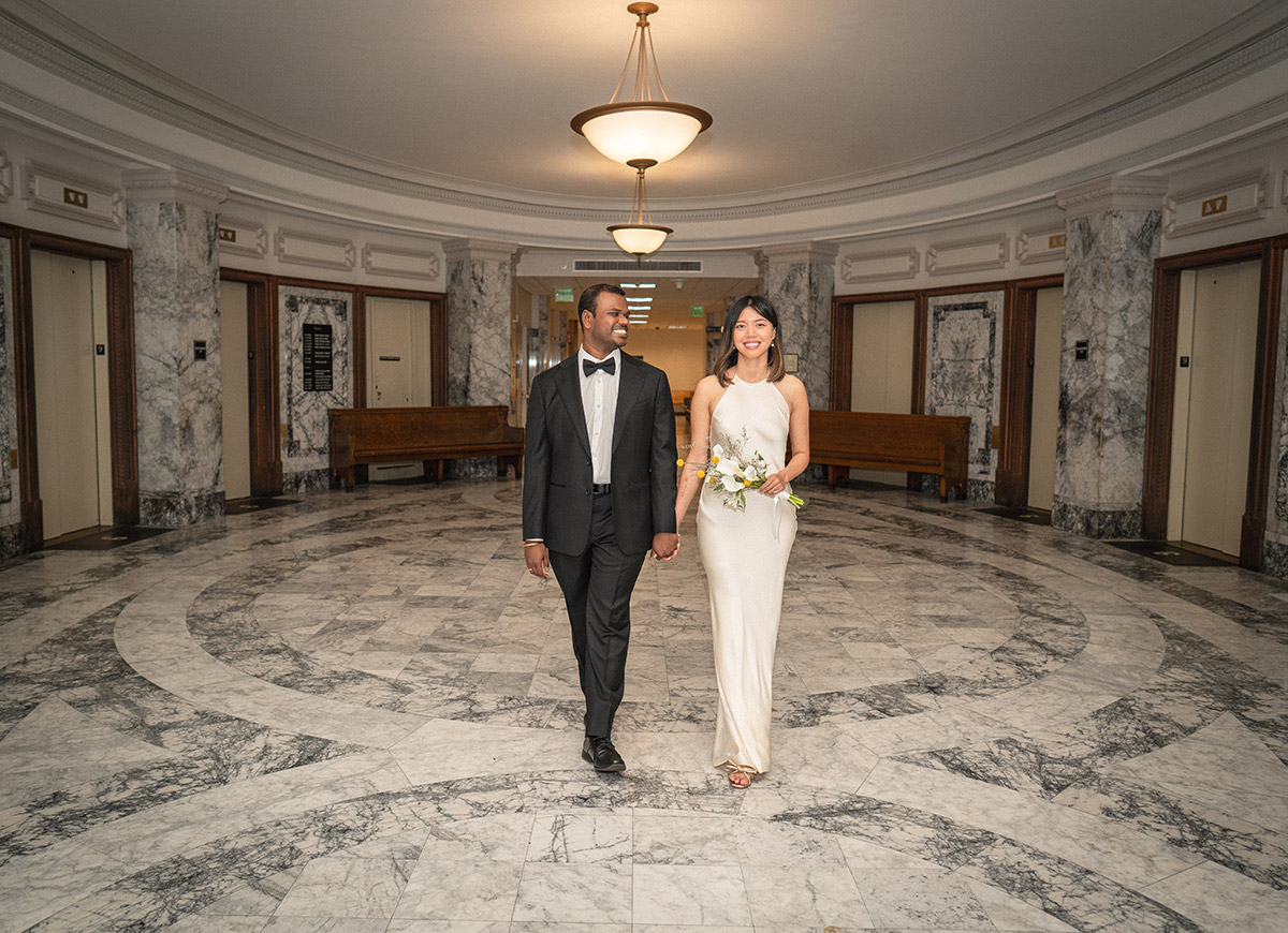 The bride and groom are walking down the city hall
