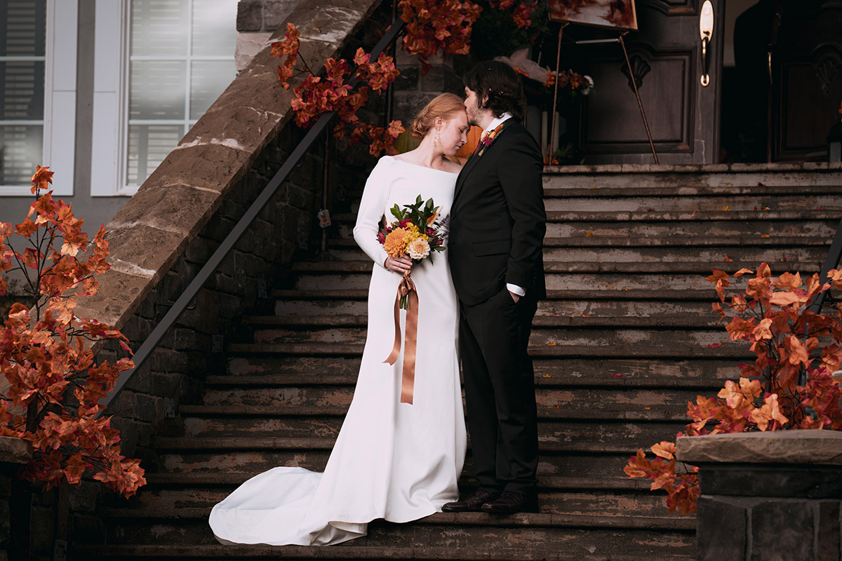 The bride and groom are on the stairs, holding each other's hands.