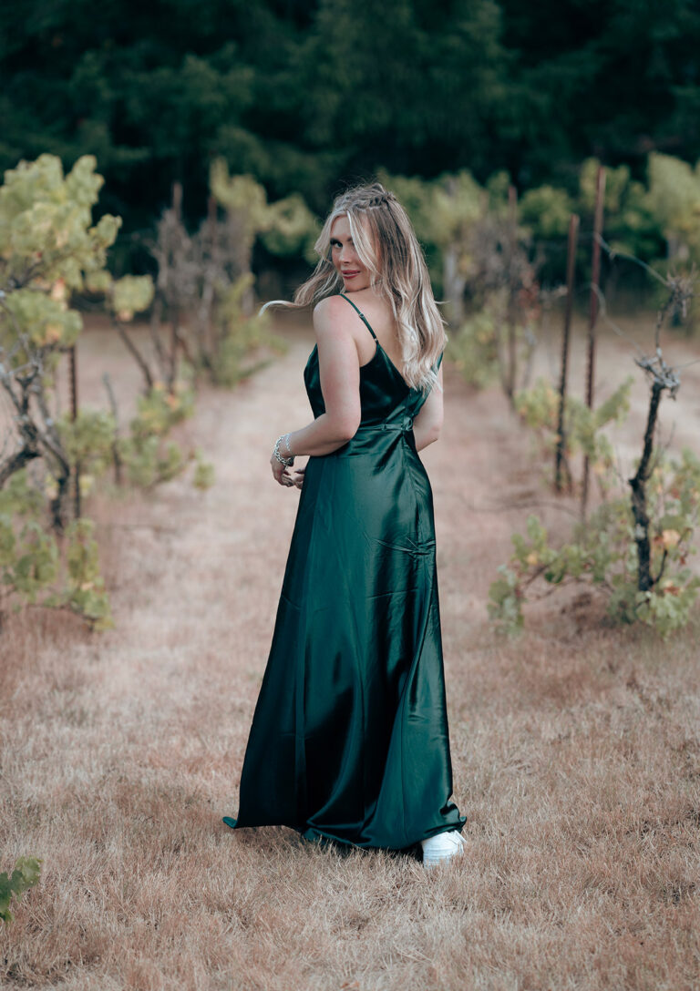 Portrait photo of a woman in green dress walking in a field staring at camera