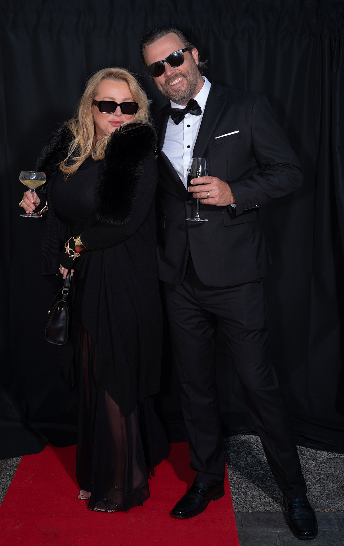 A couple standing on red carpet with fancy dresses