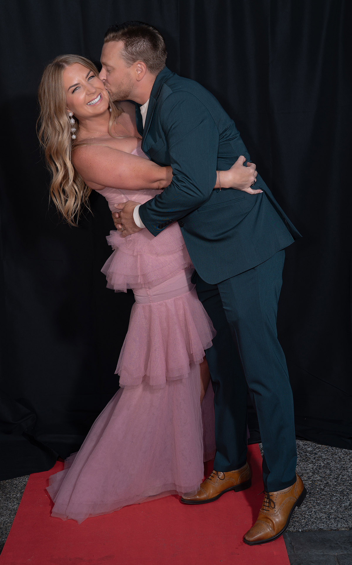 A couple standing on red carpet with fancy dresses