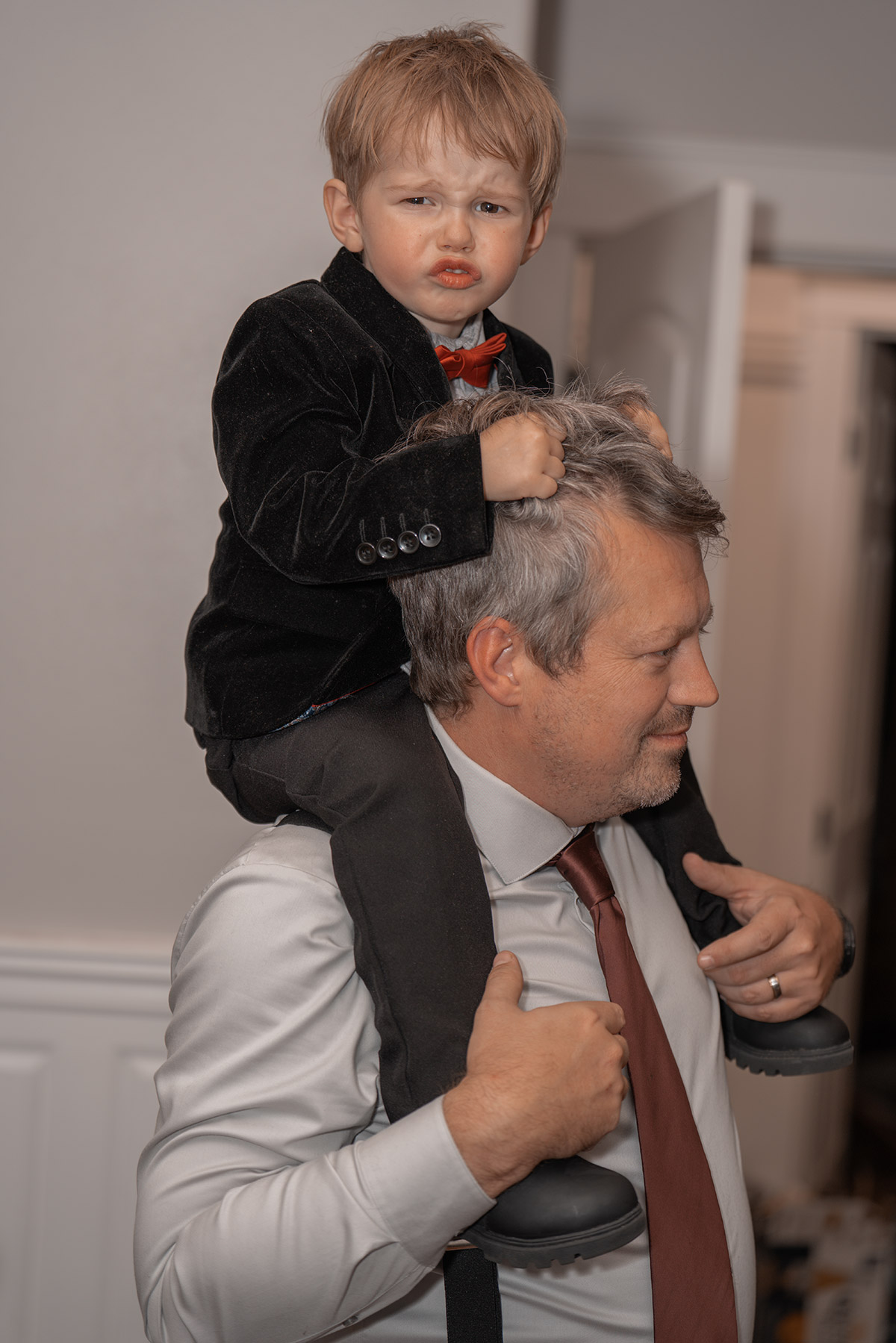 A kid riding on his dad's shoulder