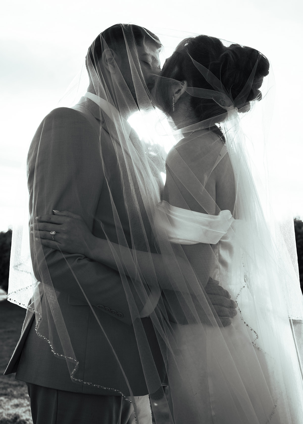 A black and white wedding portrait of a couple kissing each othe
