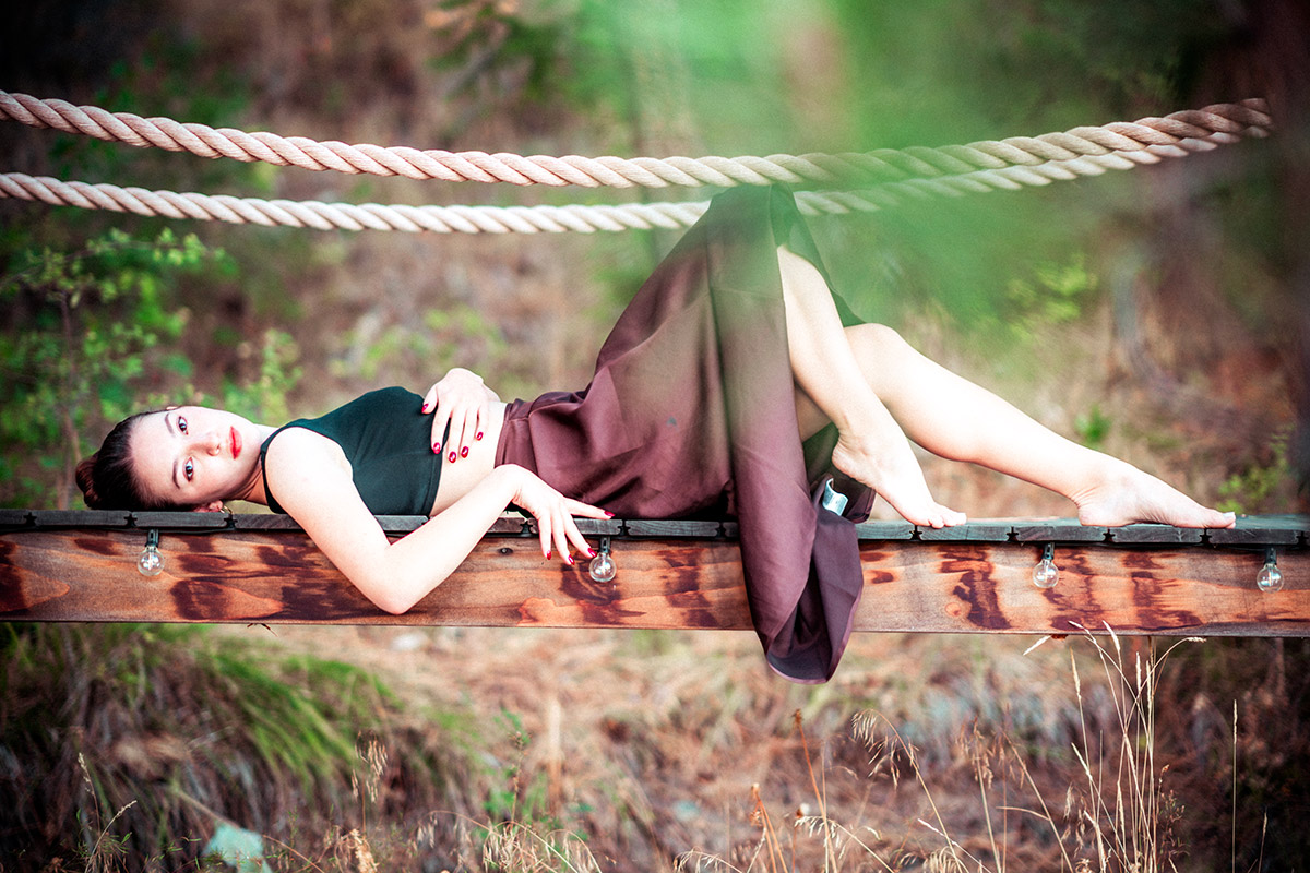 Portrait photo of a girl with white dress and brown skirt on a bridge