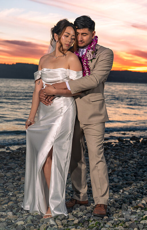 Wedding picture of a couple with sunset backdrop and holding each other
