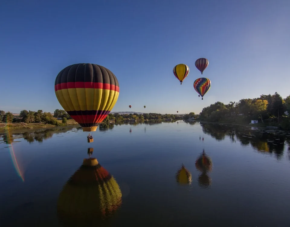 several hot air balloons flying over a lake in Seattle