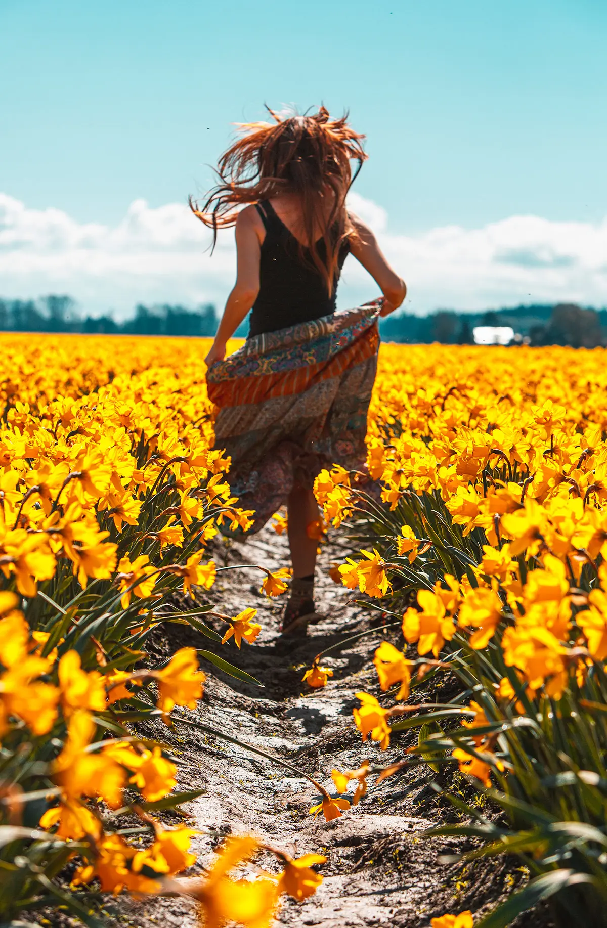 A girl's photo running in a field full of yellow flowers.